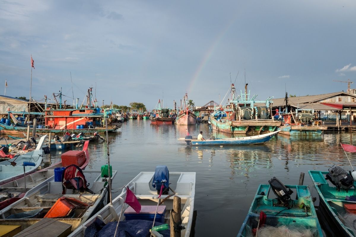 fishing village hoi an with boats docked under a rainbow sky